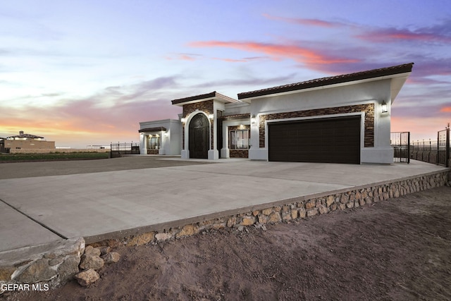 view of front of house featuring a garage, concrete driveway, fence, and stucco siding