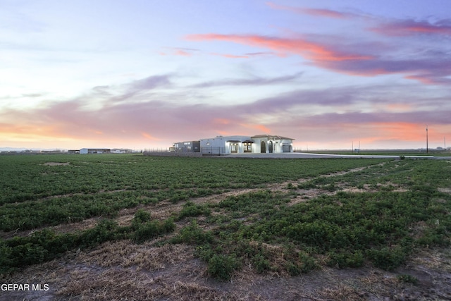 yard at dusk featuring a rural view