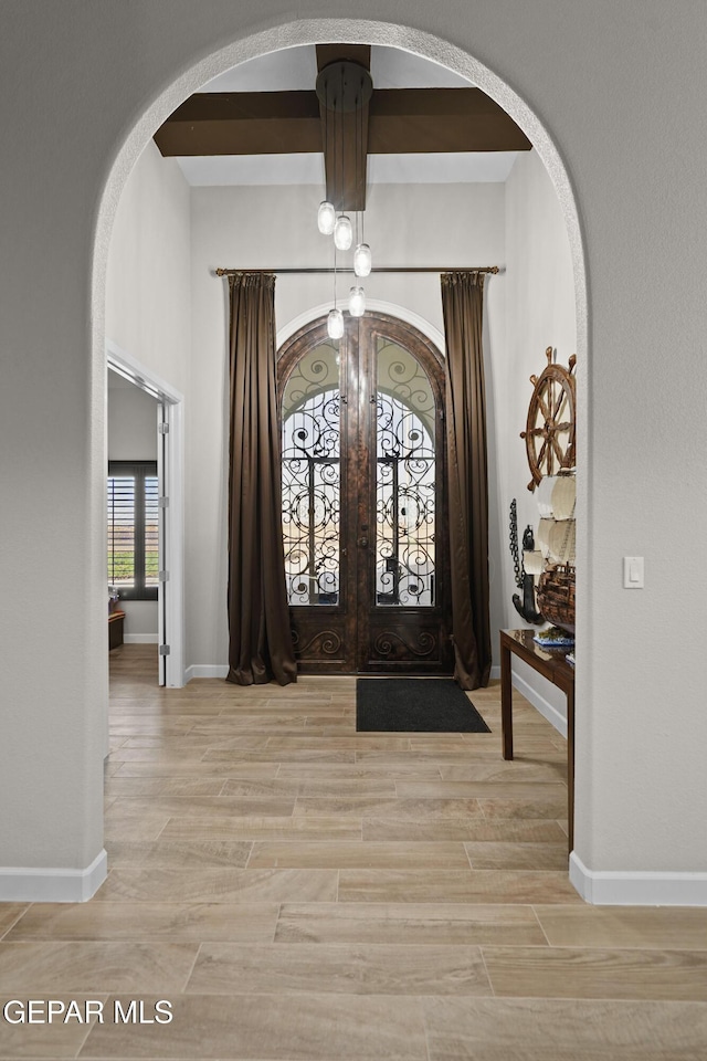 entrance foyer featuring arched walkways, light wood-type flooring, and baseboards