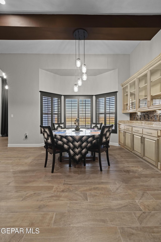 dining room with light wood-type flooring, beamed ceiling, and baseboards