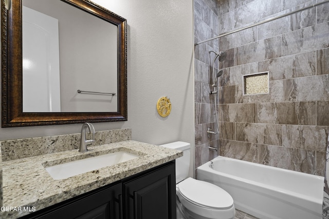 bathroom featuring toilet, a textured wall, shower / washtub combination, and vanity