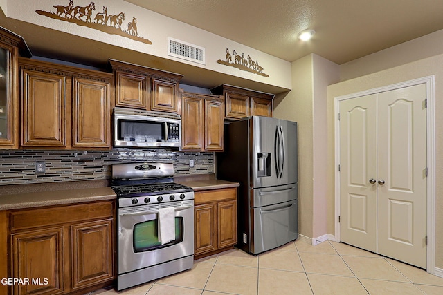 3537 Tierra Bahia Dr, El Paso, TX 79938 - kitchen featuring brown cabinets, light tile patterned floors, visible vents, and stainless steel appliances