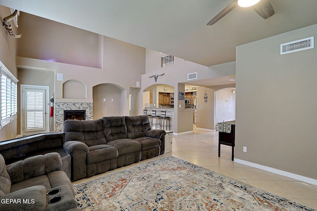 3537 Tierra Bahia Dr, El Paso, TX 79938 - living room with light tile patterned floors, visible vents, arched walkways, a ceiling fan, and a fireplace