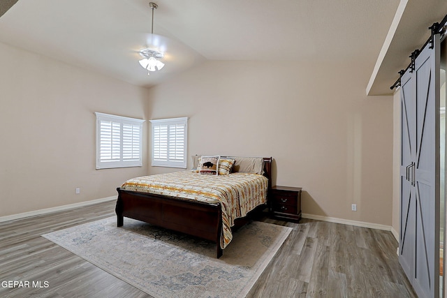 3537 Tierra Bahia Dr, El Paso, TX 79938 - bedroom with a barn door, baseboards, vaulted ceiling, and wood finished floors