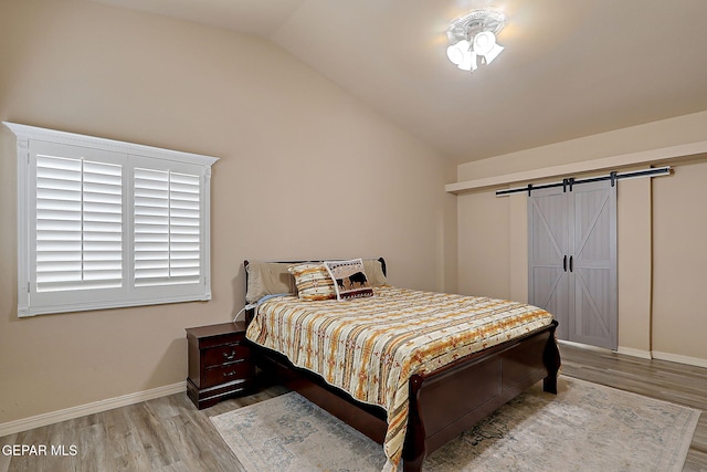 3537 Tierra Bahia Dr, El Paso, TX 79938 - bedroom featuring lofted ceiling, wood finished floors, baseboards, and a barn door