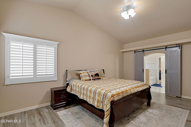 3537 Tierra Bahia Dr, El Paso, TX 79938 - bedroom featuring lofted ceiling, a barn door, wood finished floors, and baseboards
