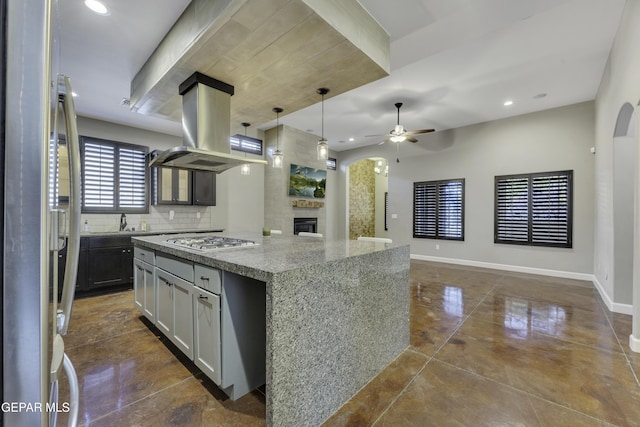 kitchen with a center island, appliances with stainless steel finishes, open floor plan, island range hood, and light stone countertops