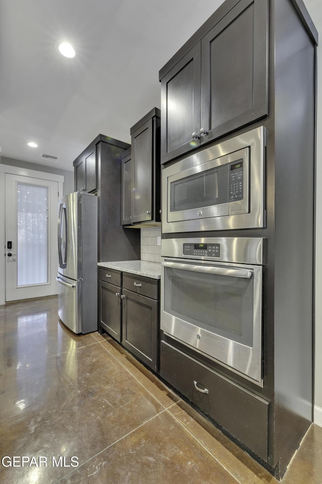 kitchen with light stone countertops, recessed lighting, visible vents, appliances with stainless steel finishes, and decorative backsplash