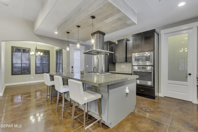 kitchen featuring stainless steel appliances, hanging light fixtures, a kitchen island, dark stone counters, and a kitchen breakfast bar