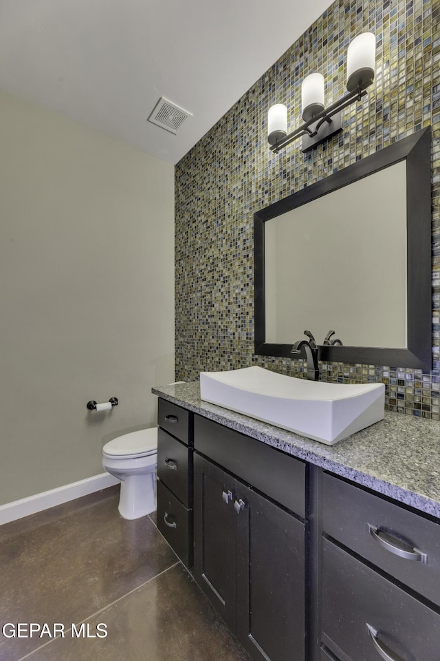 bathroom featuring baseboards, visible vents, toilet, concrete flooring, and vanity