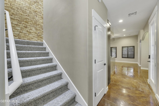 stairs featuring recessed lighting, brick wall, visible vents, baseboards, and finished concrete floors