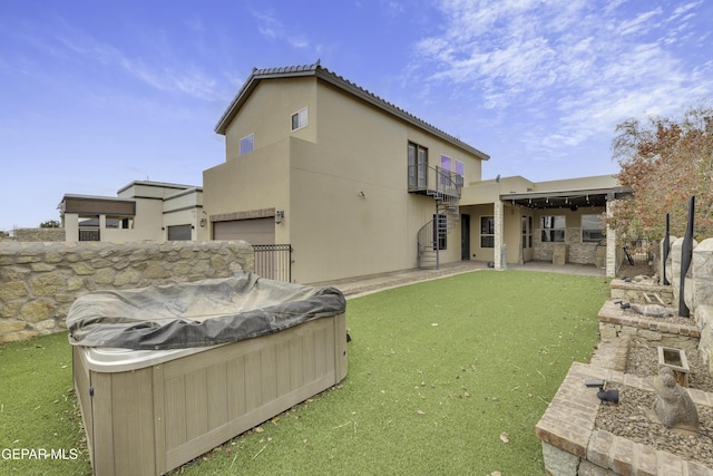 rear view of house with a balcony, a tile roof, a lawn, stucco siding, and a hot tub