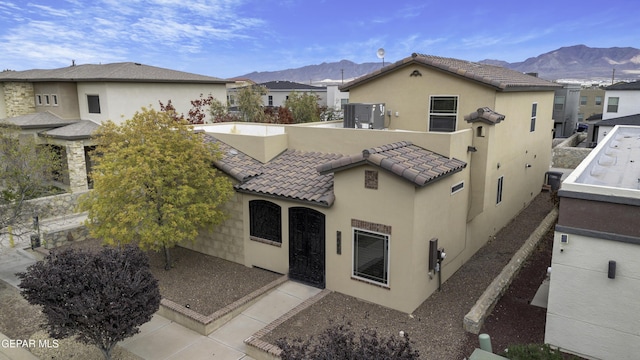 view of front facade with a residential view, a mountain view, a tiled roof, and stucco siding