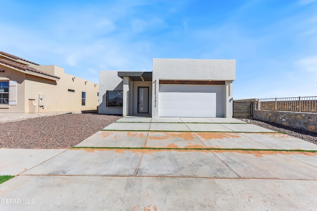 view of front of property with a garage, concrete driveway, fence, and stucco siding