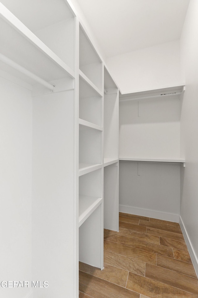 walk in closet with wood finish floors