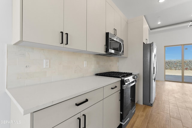 kitchen with stainless steel appliances, decorative backsplash, light countertops, and white cabinets