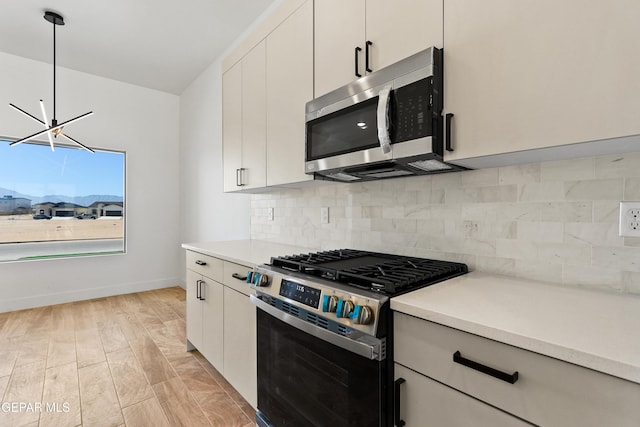 kitchen featuring stainless steel appliances, light countertops, white cabinets, and pendant lighting