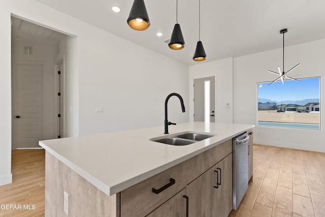 kitchen with an island with sink, a sink, hanging light fixtures, light countertops, and stainless steel dishwasher