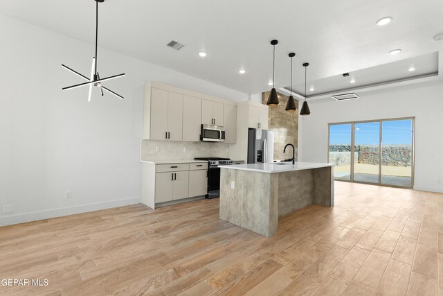 kitchen with stainless steel appliances, white cabinetry, an island with sink, and modern cabinets