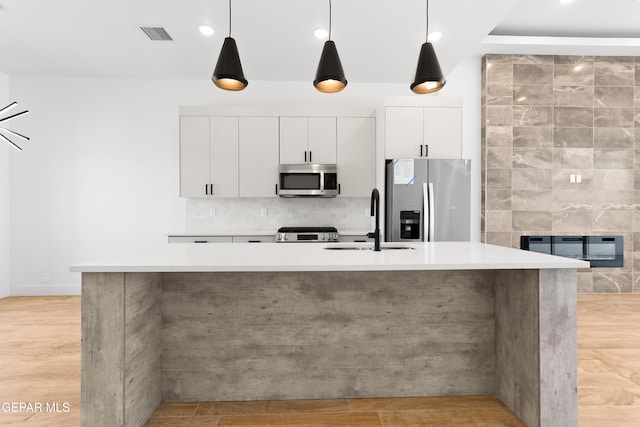 kitchen featuring white cabinets, appliances with stainless steel finishes, light countertops, and decorative light fixtures