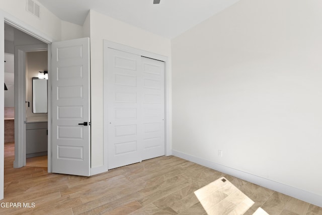 unfurnished bedroom with light wood-style floors, visible vents, baseboards, and a closet