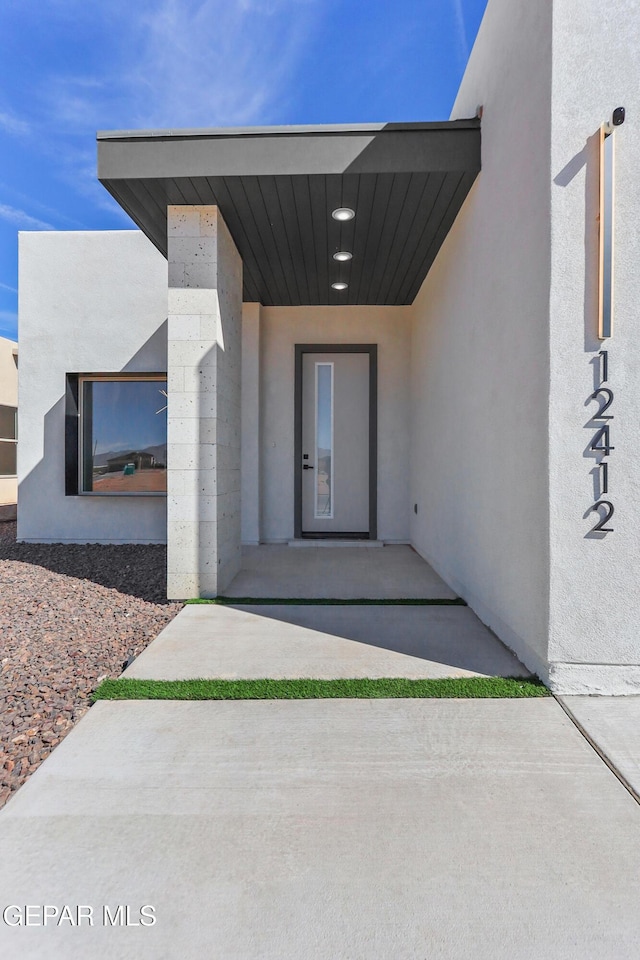 view of exterior entry featuring a patio area and stucco siding