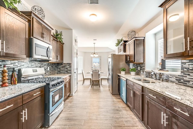 14291 Armando Silva Dr, El Paso, TX 79938 - kitchen with glass insert cabinets, stainless steel appliances, light wood-style floors, pendant lighting, and a sink