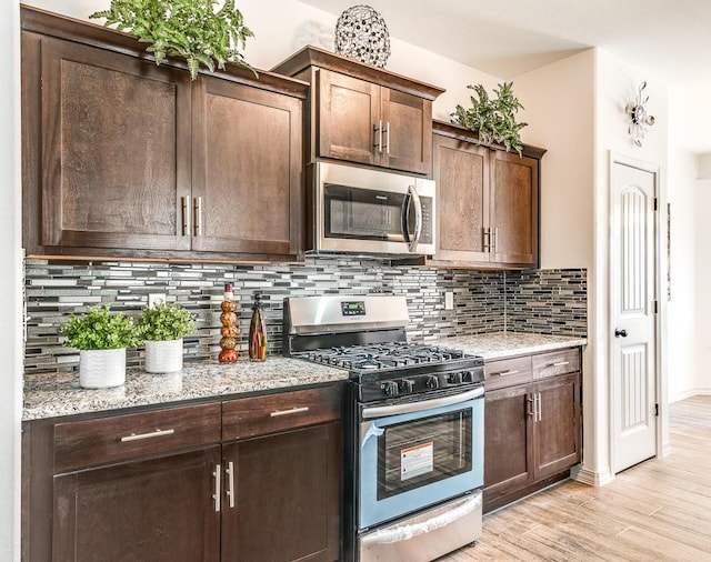 14291 Armando Silva Dr, El Paso, TX 79938 - kitchen featuring light wood-style flooring, appliances with stainless steel finishes, light stone counters, dark brown cabinets, and backsplash