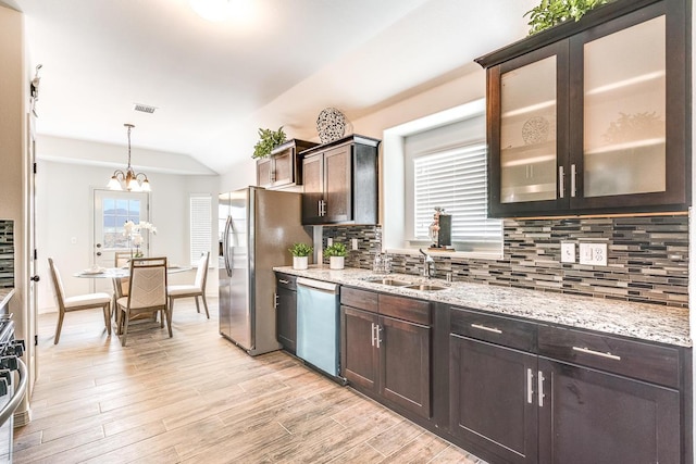 14291 Armando Silva Dr, El Paso, TX 79938 - kitchen with glass insert cabinets, hanging light fixtures, dark brown cabinets, stainless steel dishwasher, and a sink