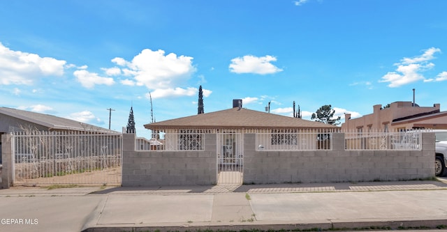 view of front facade featuring roof with shingles, a fenced front yard, and a gate