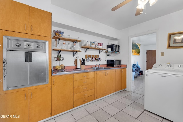 kitchen with washer / dryer, light tile patterned floors, a ceiling fan, stainless steel microwave, and a sink