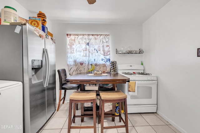 kitchen with stainless steel fridge, light tile patterned floors, baseboards, and white gas range