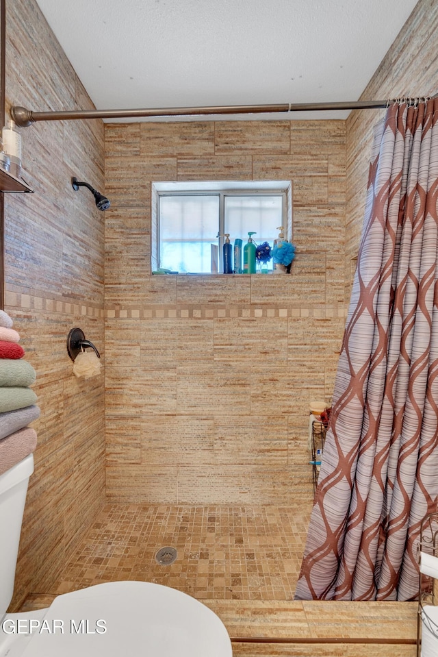 full bathroom with tiled shower, a textured ceiling, and toilet