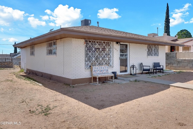 rear view of property featuring cooling unit, brick siding, fence, and a patio