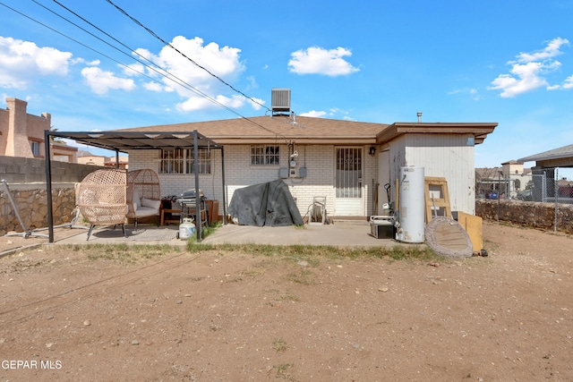 rear view of house with brick siding, a patio, water heater, central AC, and fence