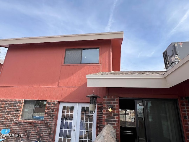 exterior space with cooling unit, french doors, and brick siding