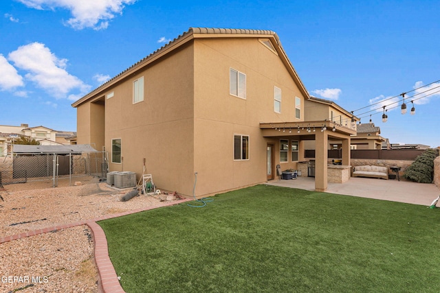 rear view of house featuring stucco siding, fence, a patio, and a yard