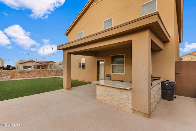 rear view of property with a yard, a patio area, and stucco siding