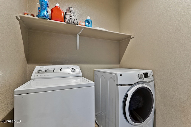 laundry room featuring a textured wall, washing machine and dryer, and laundry area