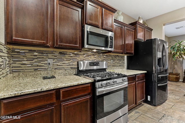 kitchen with dark brown cabinetry, stainless steel appliances, visible vents, decorative backsplash, and light stone countertops