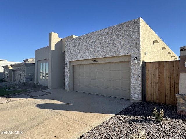 view of front facade featuring a garage, stone siding, concrete driveway, and stucco siding