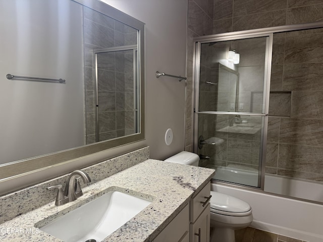 bathroom featuring bath / shower combo with glass door, vanity, and toilet