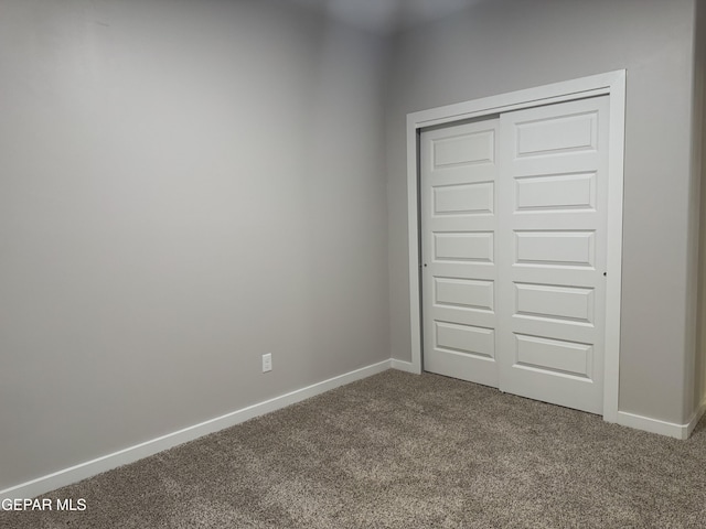 unfurnished bedroom featuring a closet, carpet, and baseboards