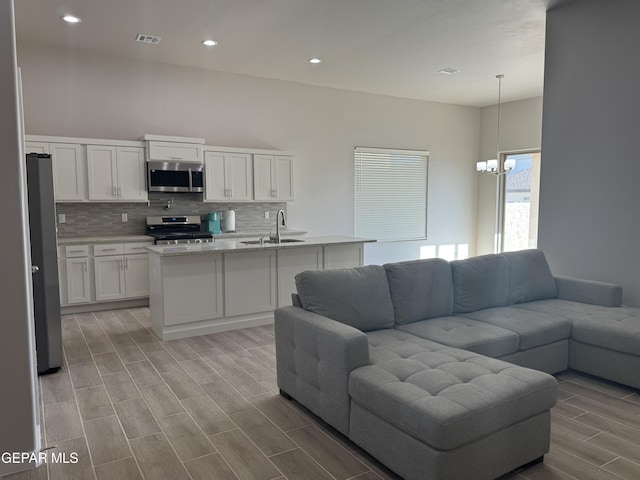 living area featuring wood finish floors, recessed lighting, visible vents, and an inviting chandelier