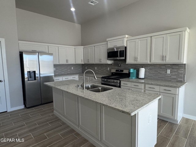 kitchen featuring an island with sink, white cabinetry, stainless steel appliances, and a sink