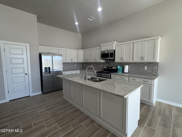 kitchen featuring a kitchen island with sink, white cabinetry, stainless steel appliances, and a sink