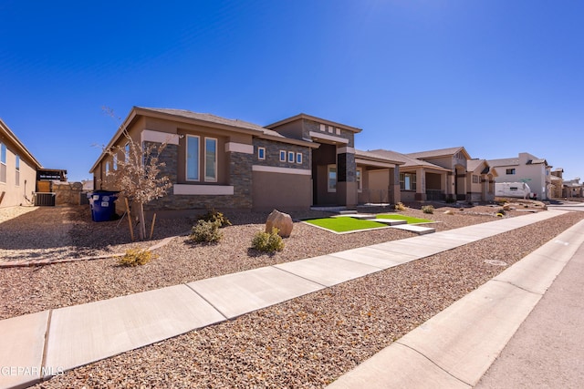 prairie-style house featuring stone siding, central AC, and stucco siding