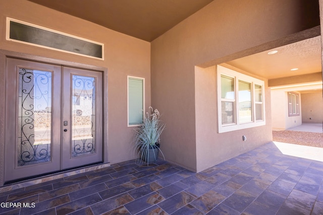 view of exterior entry with french doors, a patio, and stucco siding