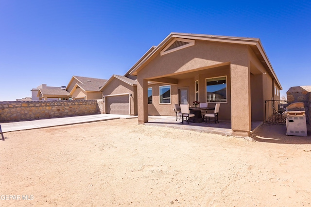 back of house featuring an attached garage, a patio area, fence, and stucco siding