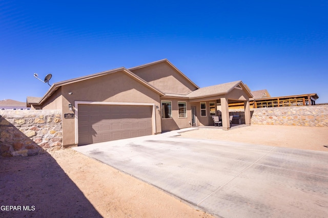 single story home with a garage, concrete driveway, fence, and stucco siding